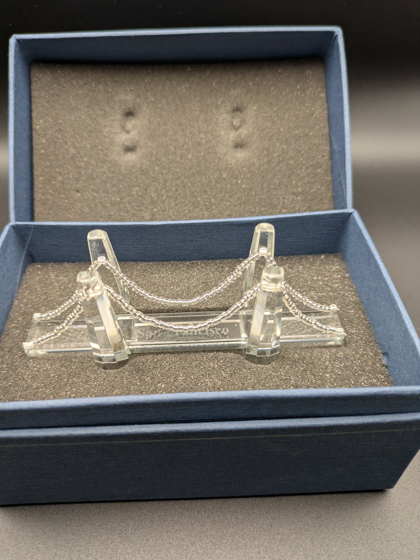 Clear miniature bridge model in a blue box with gray interior