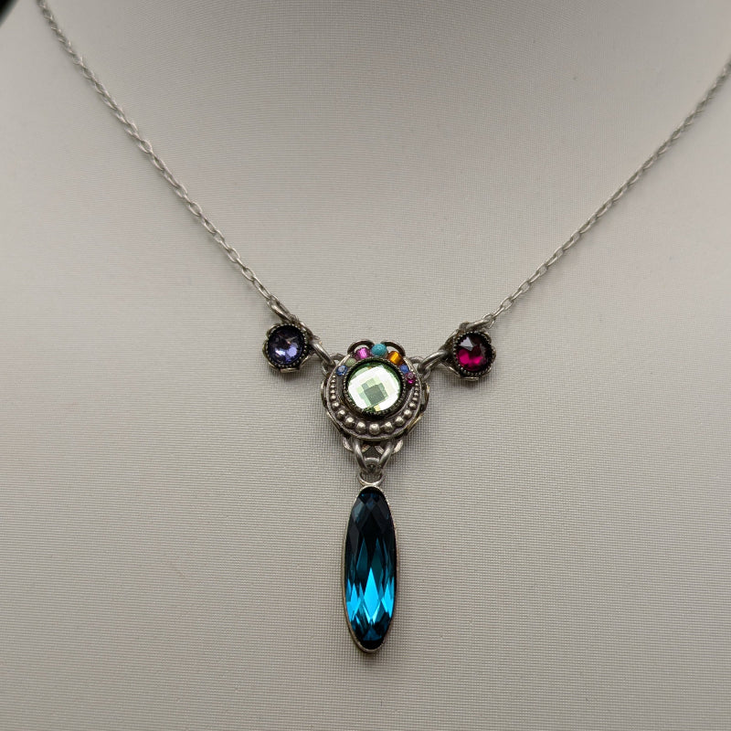 Necklace with a pendant featuring a blue teardrop and multicolored stones on a mannequin.