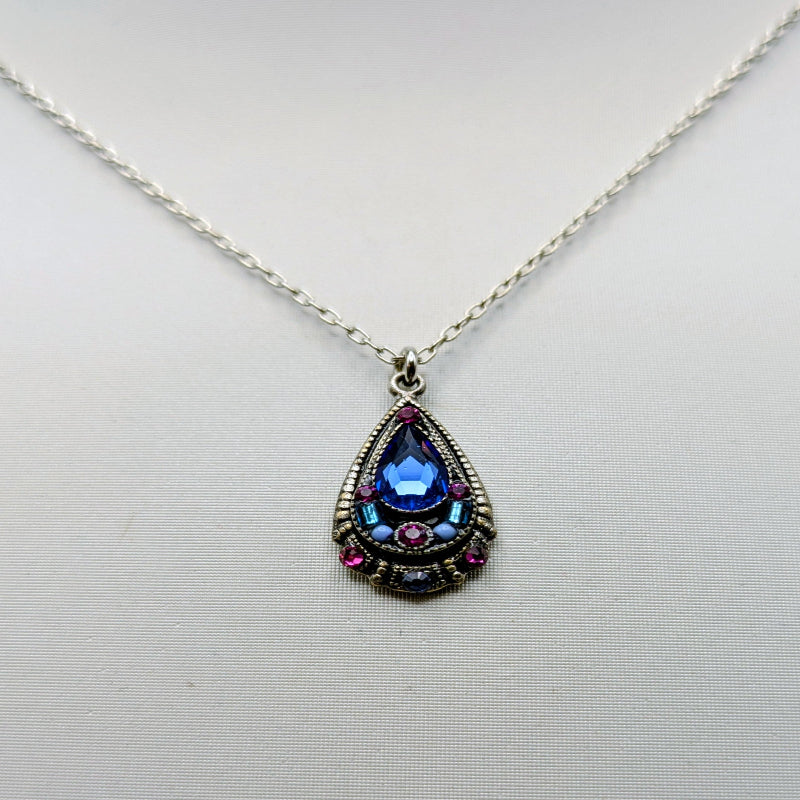 Teardrop-shaped pendant with blue gemstone on a white background