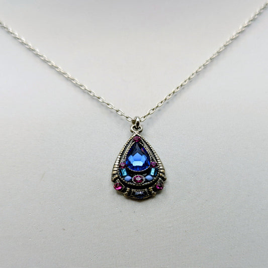 Teardrop-shaped pendant with blue gemstone on a white background