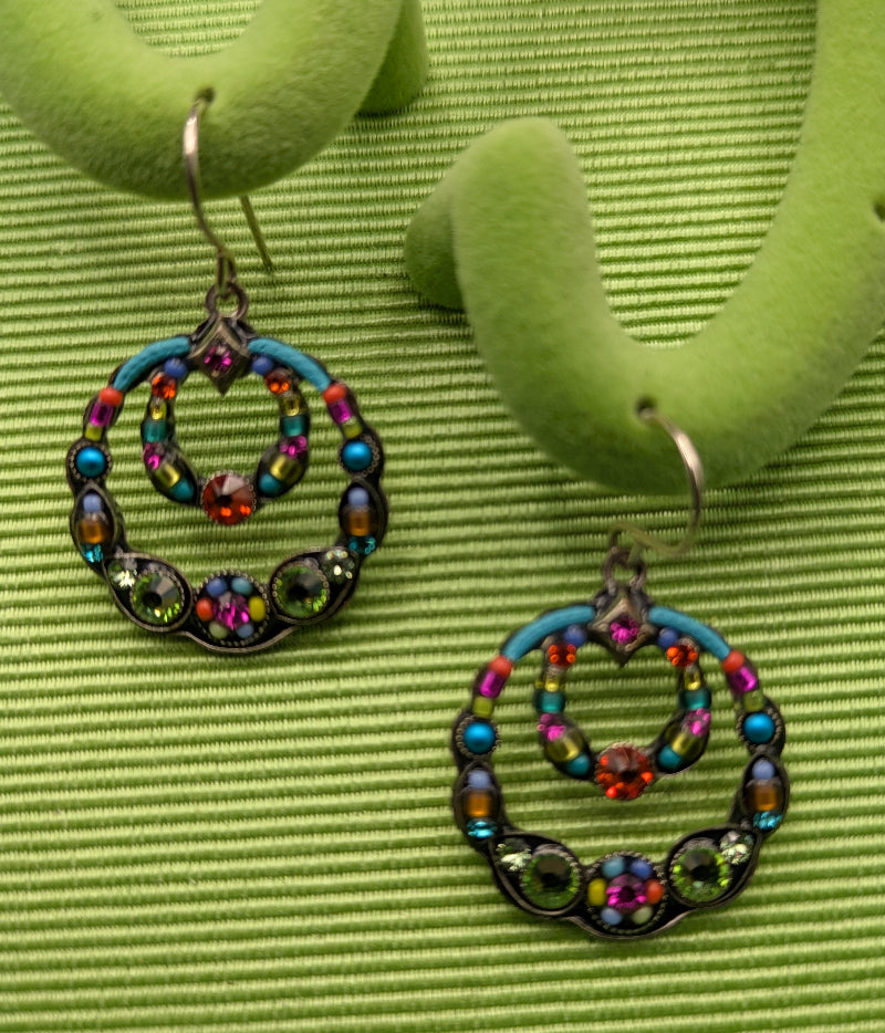 Colorful beaded hoop earrings on a green textured surface