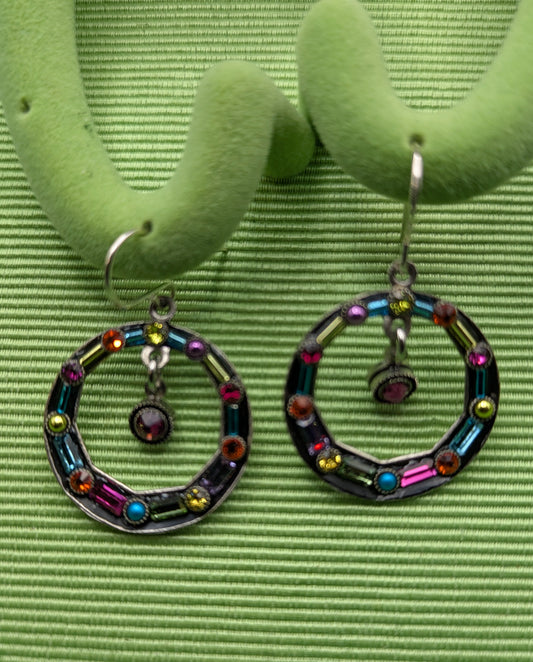 Colorful hoop earrings on a green earring stand