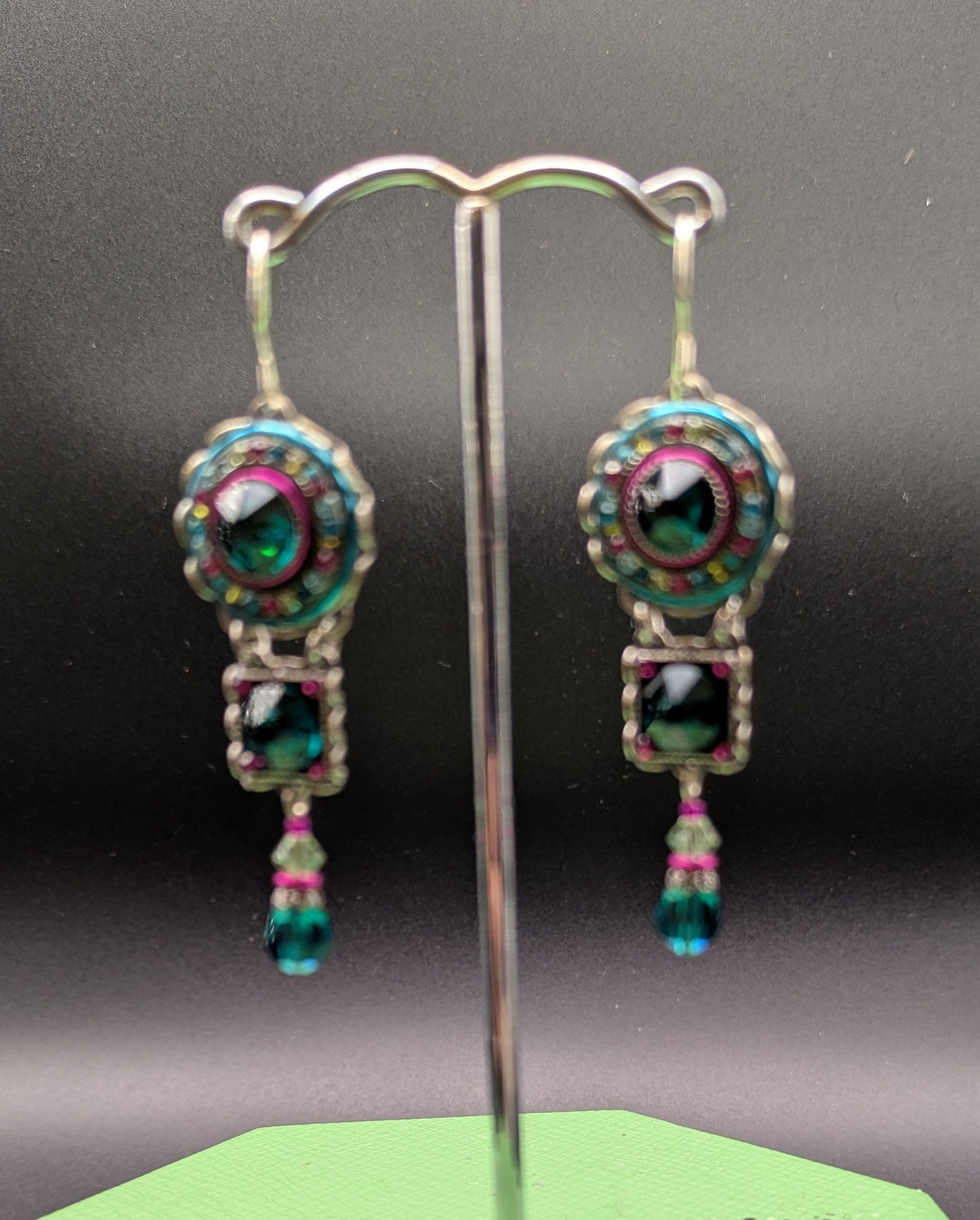 Pair of earrings on a stand with a green base