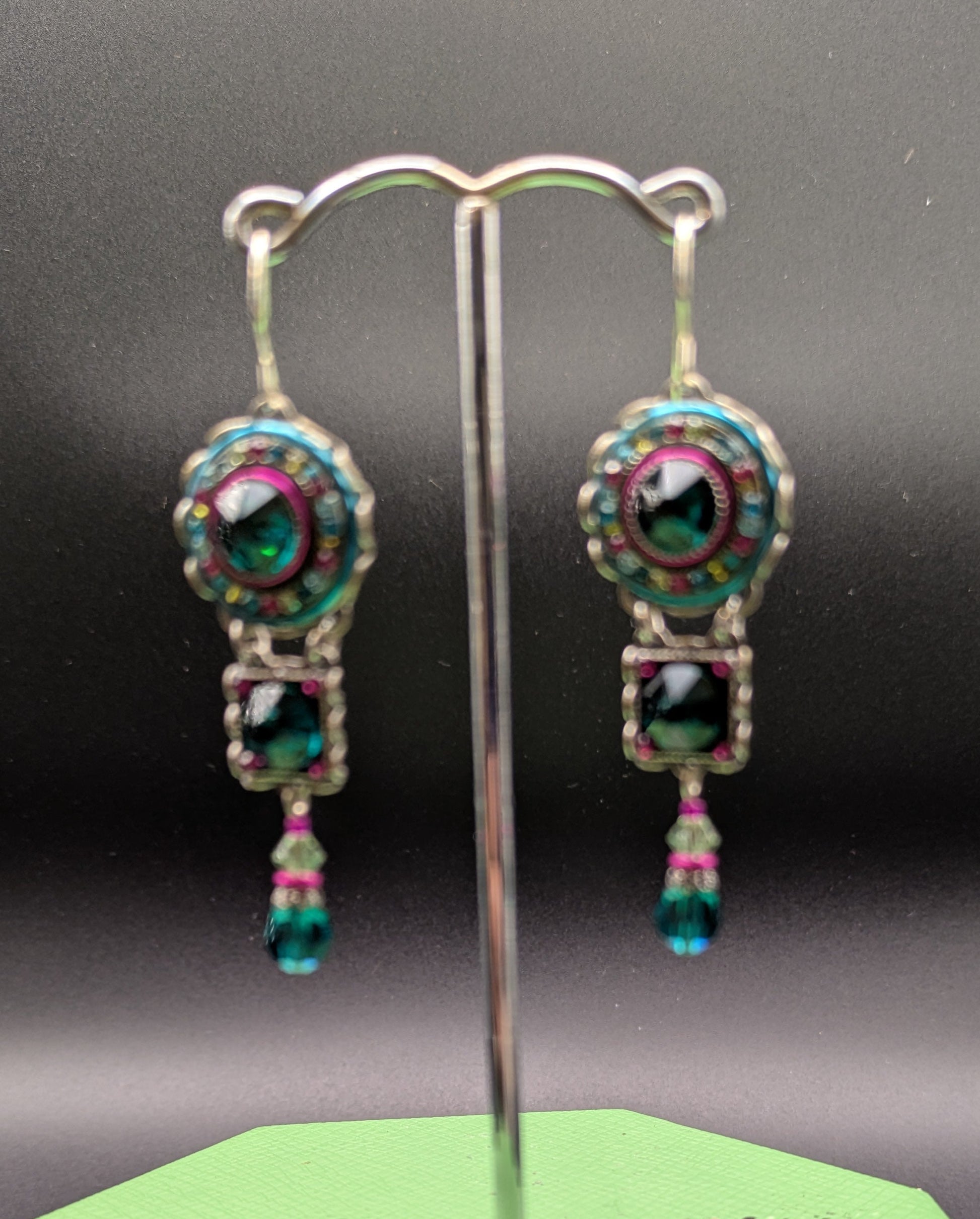 Pair of earrings on a stand with a green base