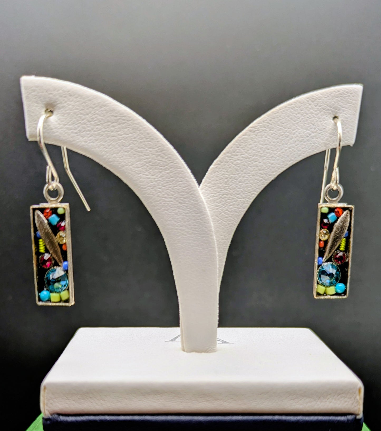 Pair of earrings on a white jewelry stand against a gray background