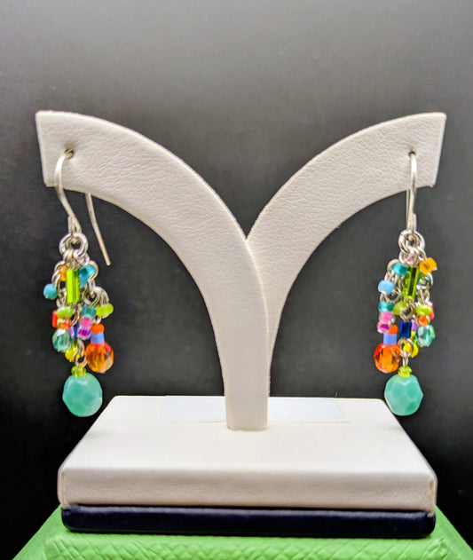 Colorful beaded earrings on a white earring stand against a black background