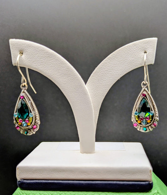 Teardrop-shaped earrings with colorful gemstones on a white stand against a black background.