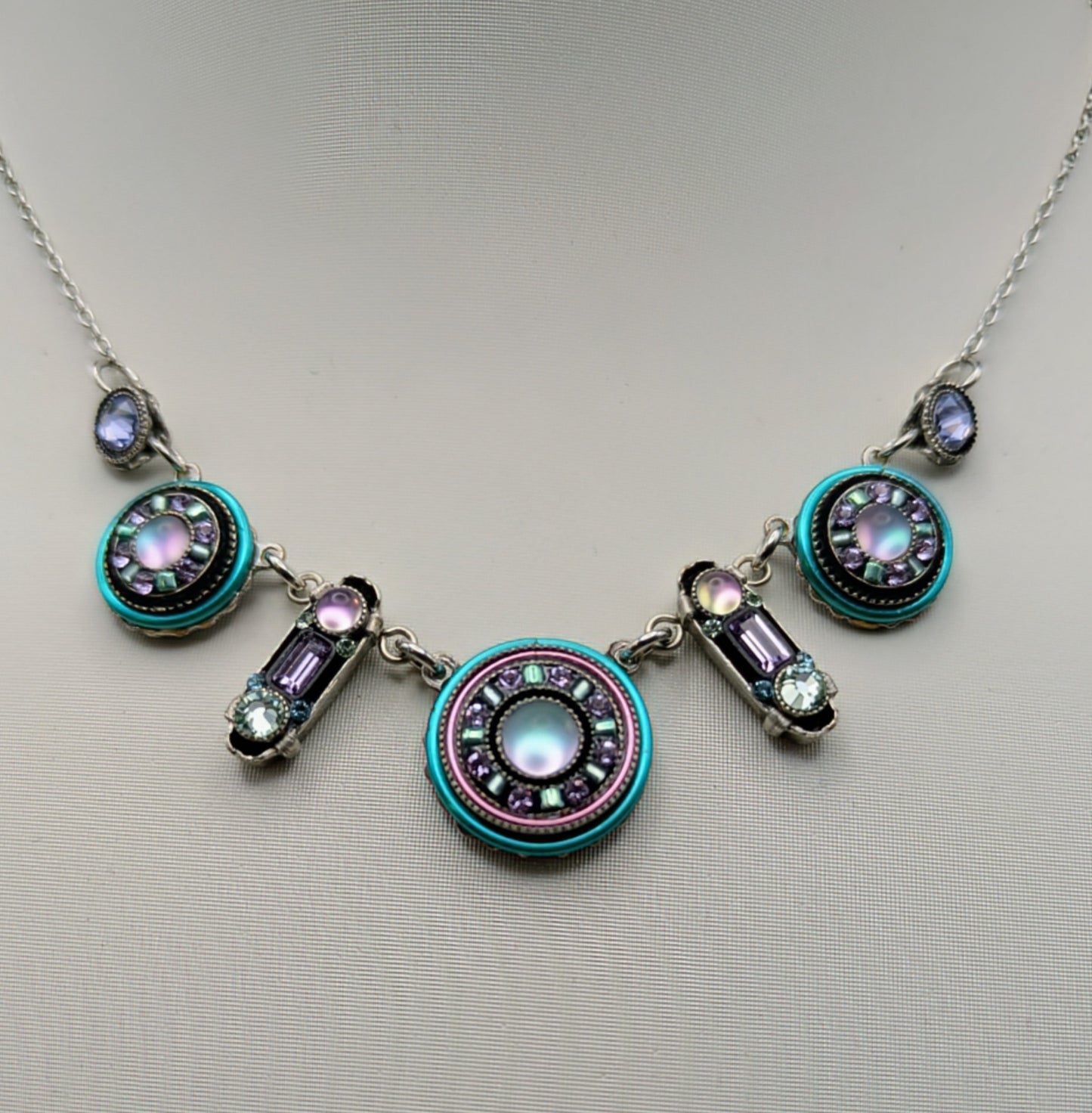 Necklace with circular pendants and gemstones on a mannequin.
