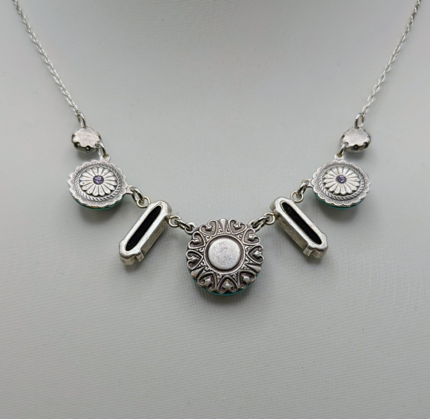 Silver necklace with circular pendants on a mannequin.