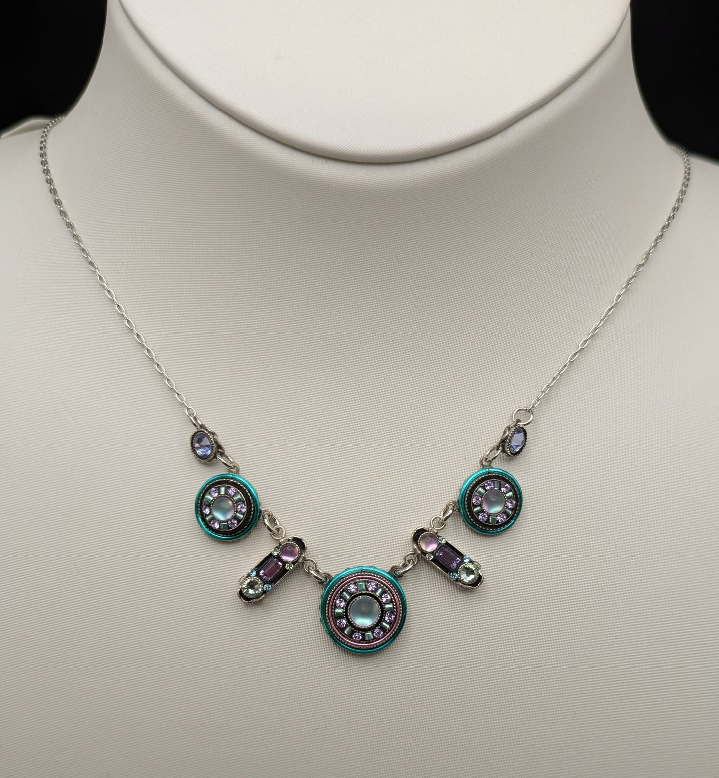 Necklace with circular pendants on a mannequin against a black background