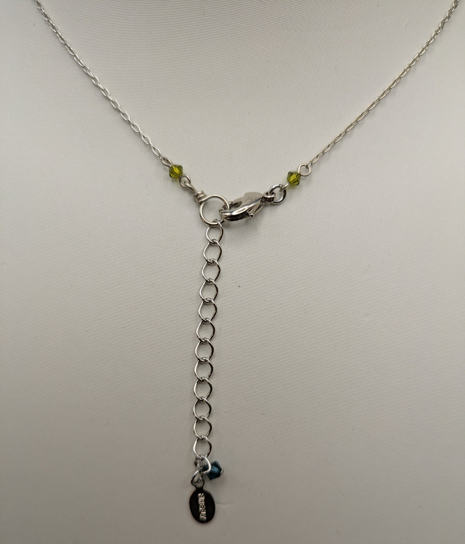 Silver necklace with a chain and pendant on a light gray background