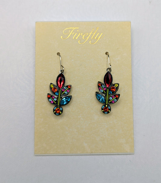 A pair of colorful dangling earrings displayed on a cream card labeled 'Firefly' inside a white box. The earrings feature a leaf-like design with red, blue, green, and orange enamel details and gold-tone hooks.