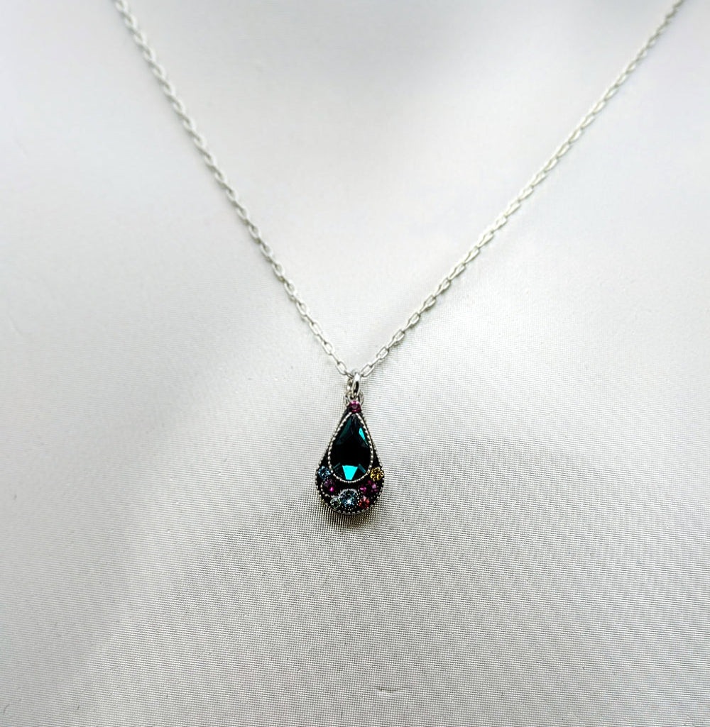 A silver chain necklace with a teardrop-shaped pendant featuring a dark green iridescent center stone surrounded by small pink and blue stones, displayed on a white fabric background.