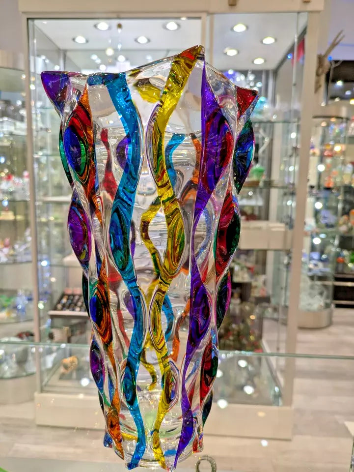 A multicolored spiral glass vase displayed in a storefront window.