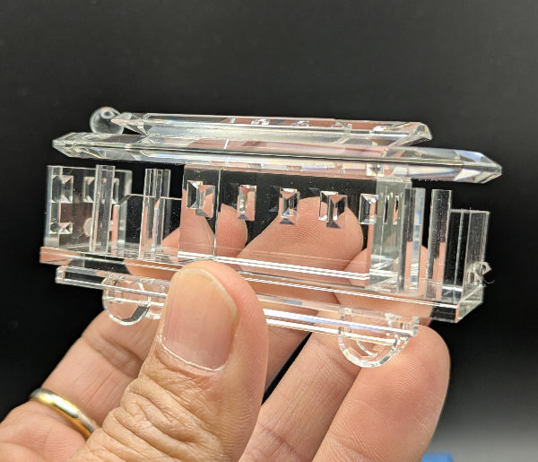 Clear tram held in a hand against a dark background