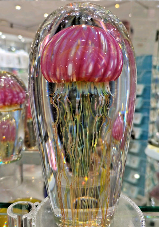 Glass jellyfish sculpture with ruby top and clear body in a store setting