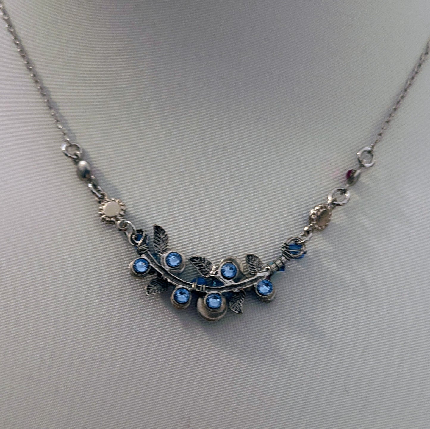 Silver necklace with blue gemstones on a light gray background