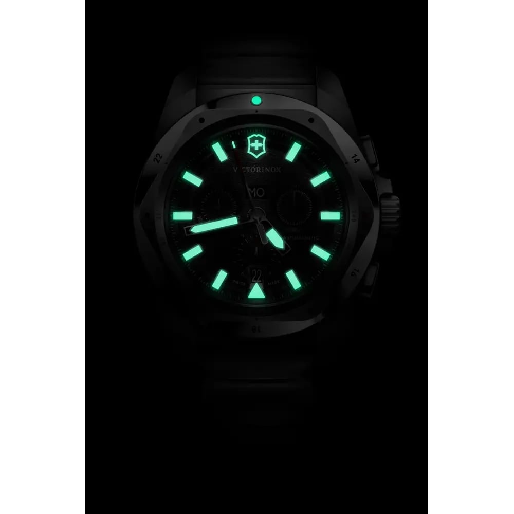 A wristwatch with a black case and dial, featuring bright green luminous hour markers, hands, and a green dot indicator on a black background.