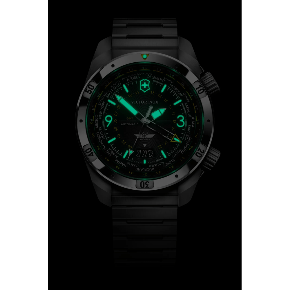 Victorinox Swiss Pilot Automatic watch with a black case and integrated black strap, featuring glowing green luminescent hands, markers, and dial details, shown against a black background.