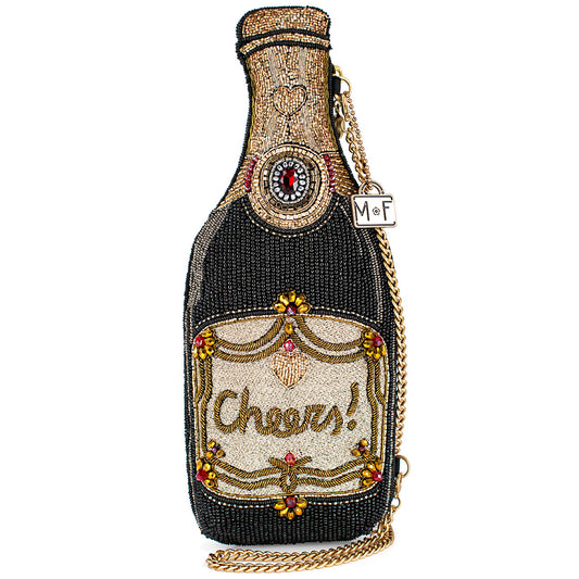 A beaded handbag designed to resemble a champagne bottle, with a 'Cheers!' text on the label and a removable chain strap.