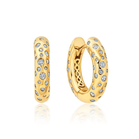 A pair of medium huggie hoop earrings finished in 18kt yellow gold with a cascading inlay of cubic zirconia.
