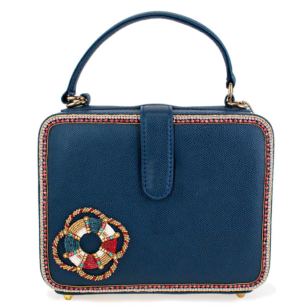 Blue handbag with decorative floral emblem on a white background