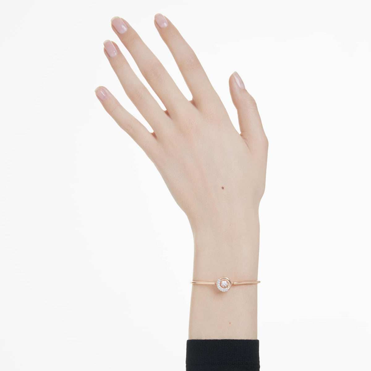 A white and rose gold-tone plated bangle bracelet with a round cut crystal centerpiece and adjustable chain on wrist.
