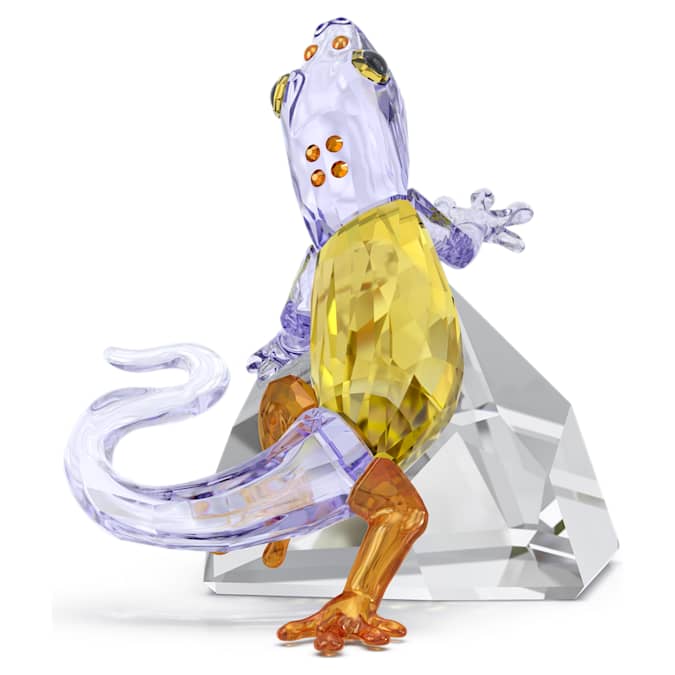 A multicolored crystal figurine of a gecko with a yellow and purple body, standing on a triangular crystal base.