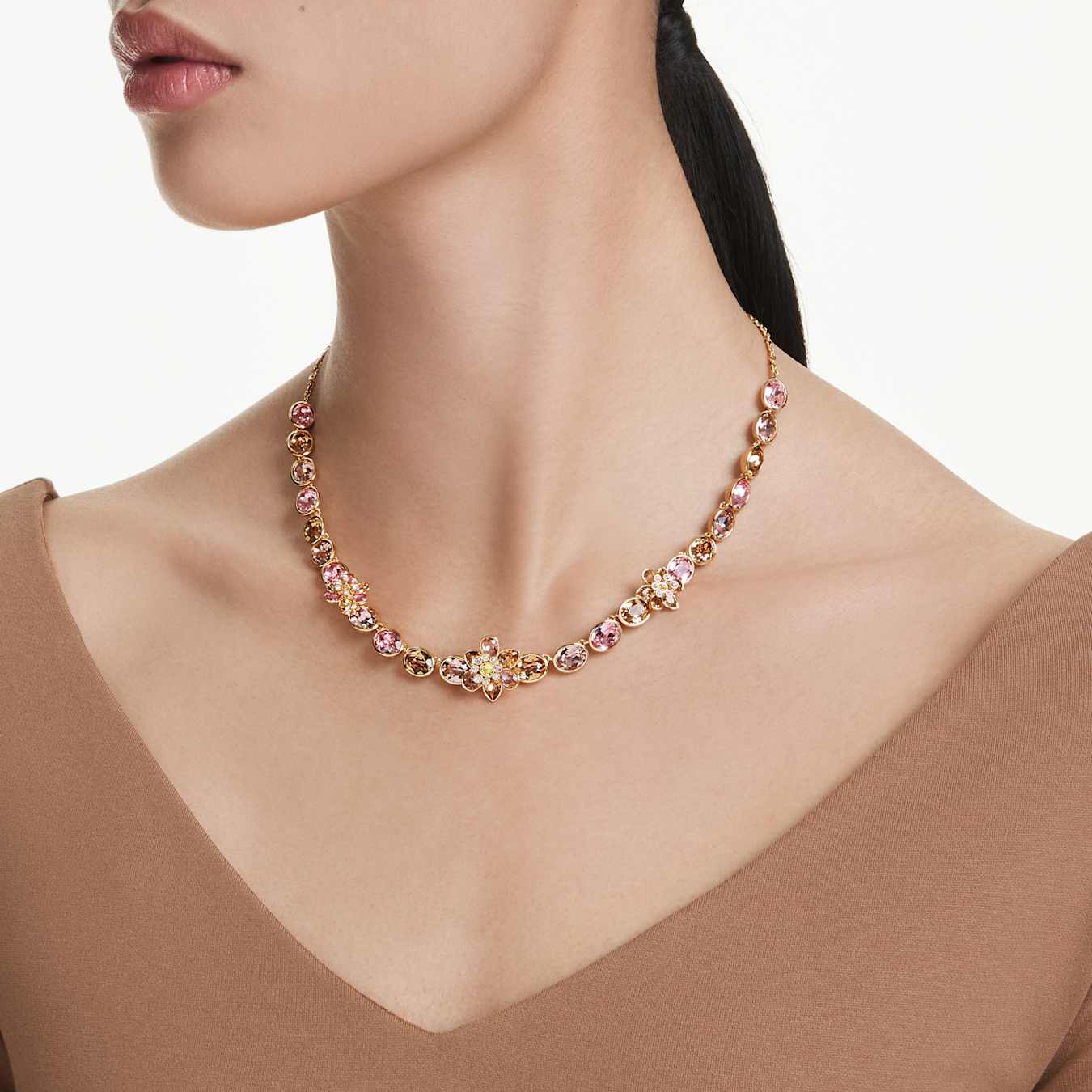 Necklace with pink and gold stones worn by a model against a neutral background