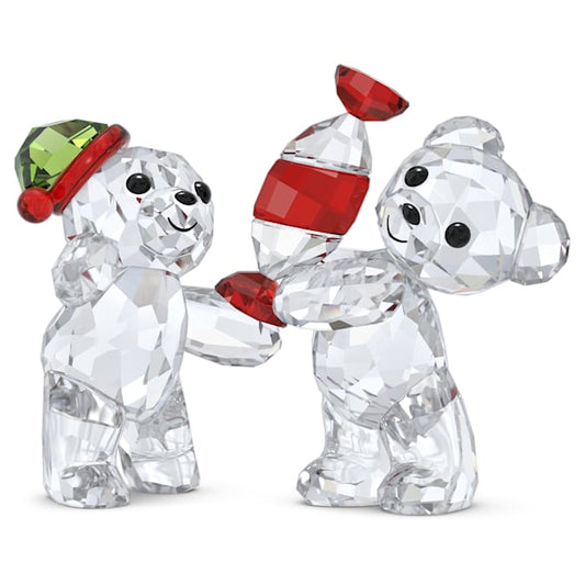 Two crystal figurines of bears, one giving a striped candy to the other, with festive red and green hats.