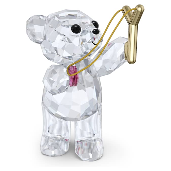 A crystal figurine of a smiling bear with a pink heart and a gold-tone metal slingshot.