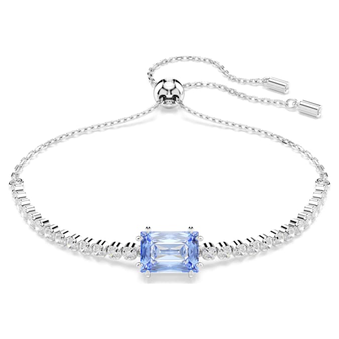 A rhodium-plated tennis bracelet with mixed cuts featuring a blue central stone, accompanied by Swarovski branding.