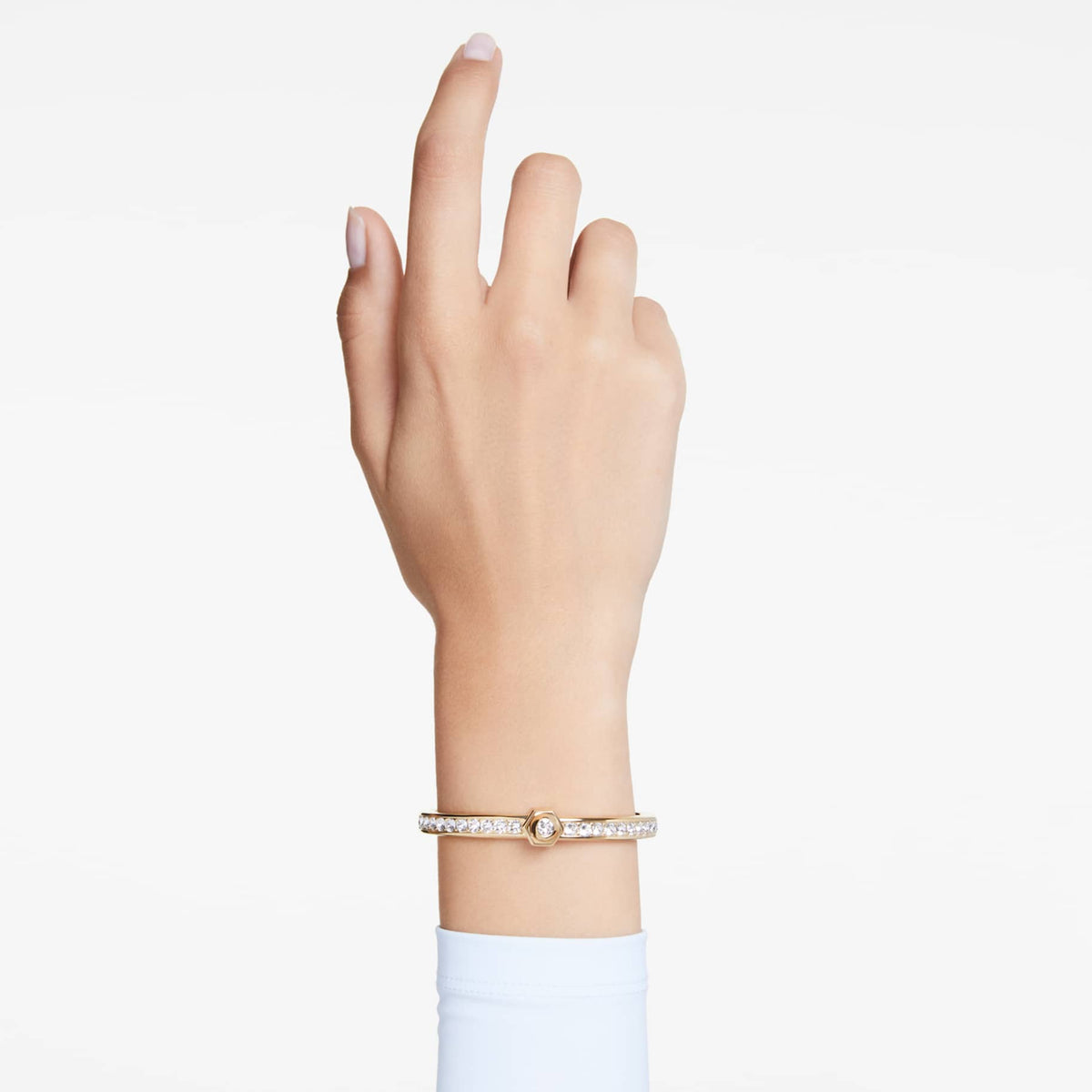Gold bracelet with clear gemstones on a white background on wrist.