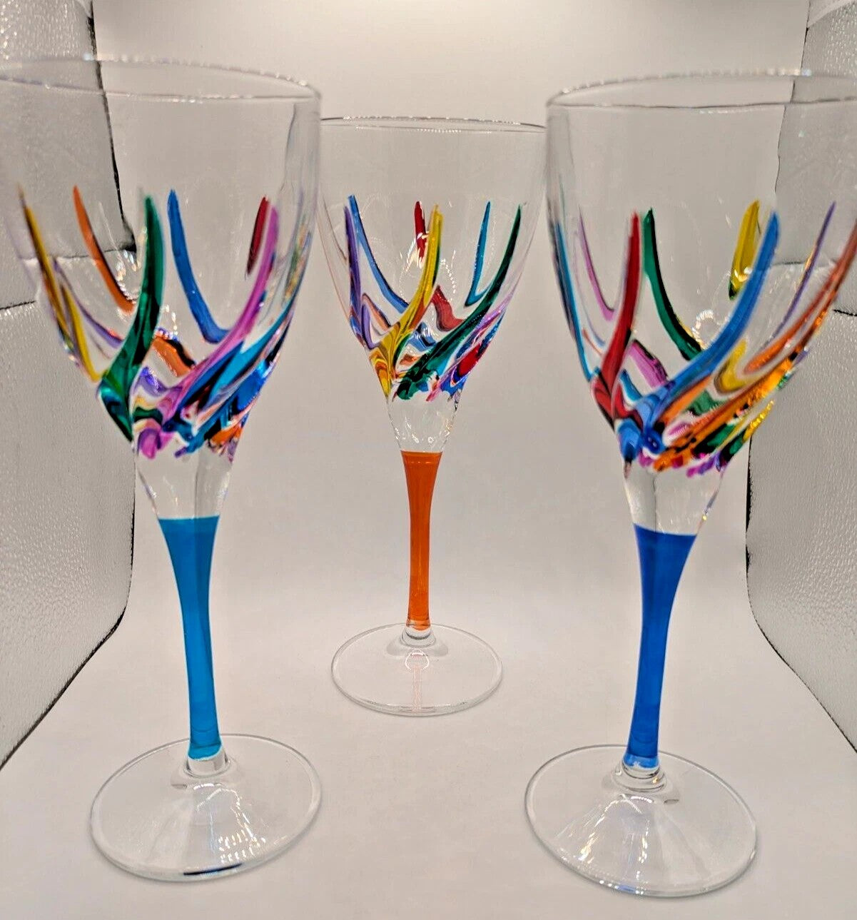 Three colorful wine glasses with rainbow patterns on a white background