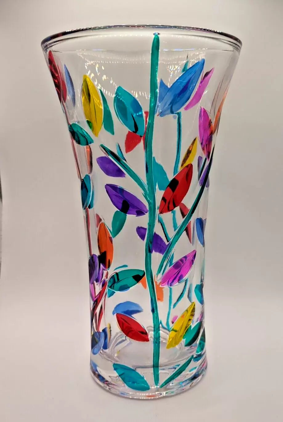 A tall Murano glass vase with a colorful leaves.