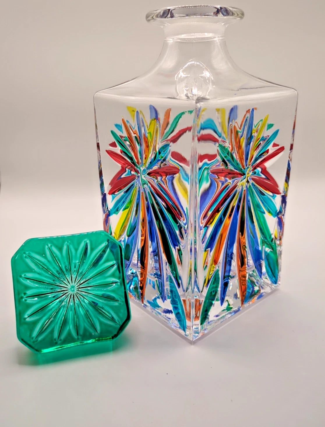 Multi color decanter with green lid on the side on white background