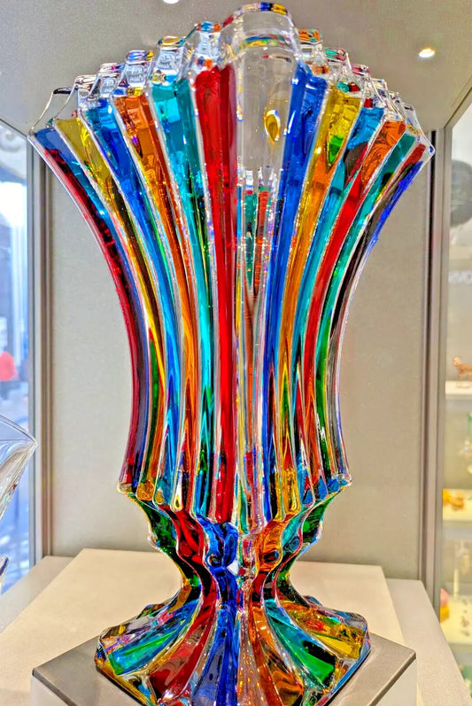 A large, multi-colored Murano glass vase displayed in a store window.
