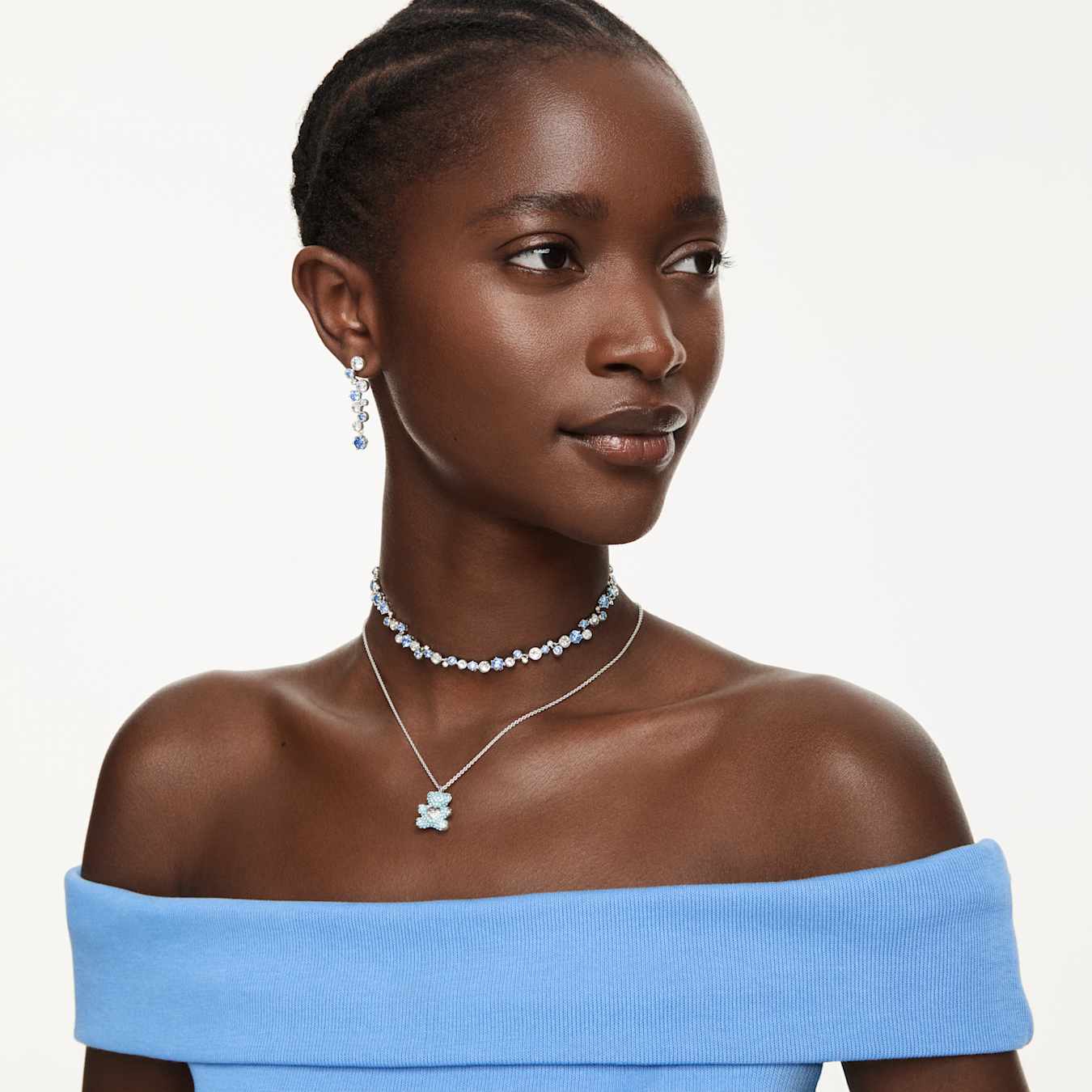 Woman wearing a necklace and earrings on a plain background