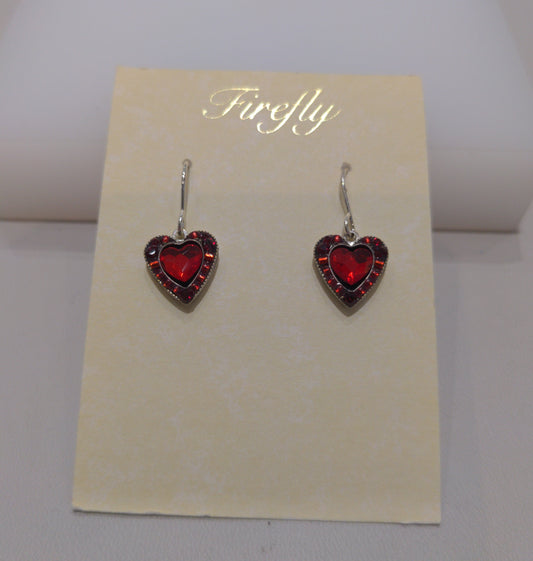 A pair of silver wire earrings with red heart-shaped embellishments, presented against a beige background in a clear case.