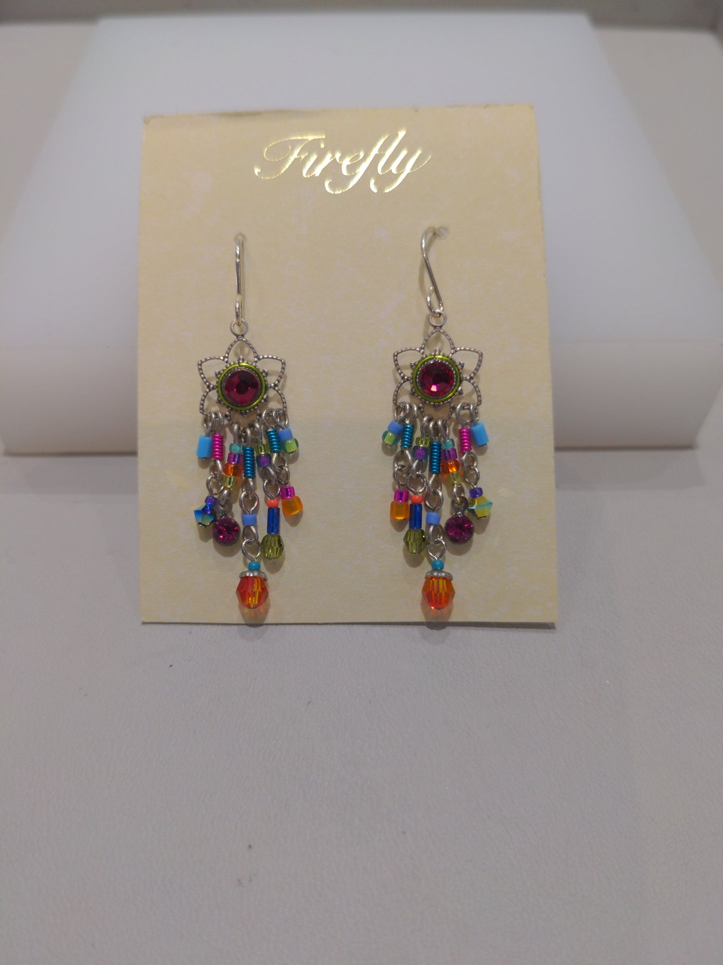 A pair of multicolored earrings with silver wire detailing and embellished with Swarovski crystals, displayed on a card.