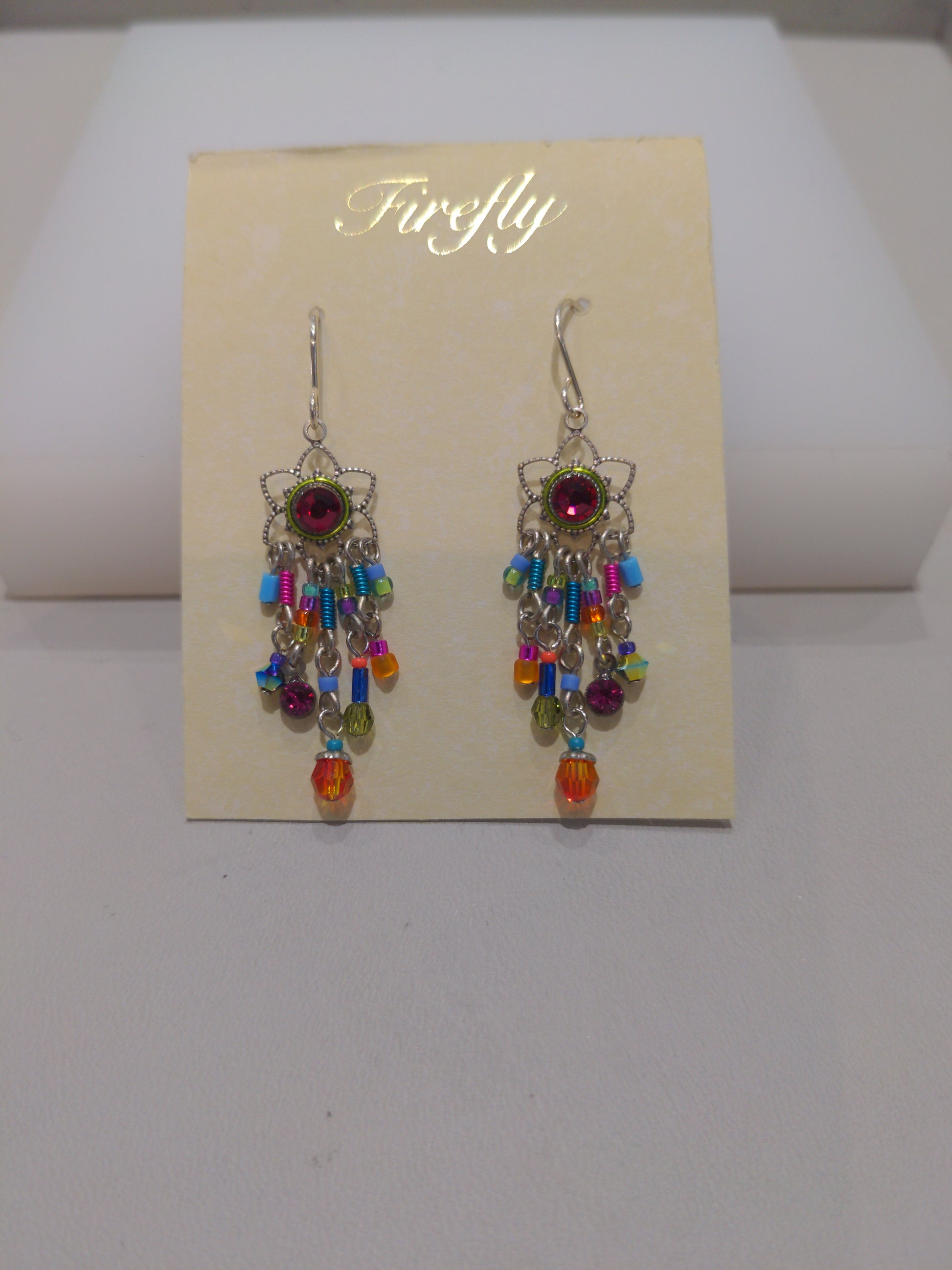 A pair of multicolored earrings with silver wire detailing and embellished with Swarovski crystals, displayed on a card.