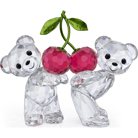 Two crystal figurines of bears holding a crystal representation of cherries, with green leaves on top, by Swarovski.