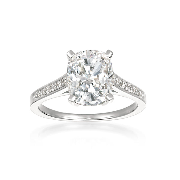 A cushion cut diamond ring with smaller stones set in a band, finished in platinum.