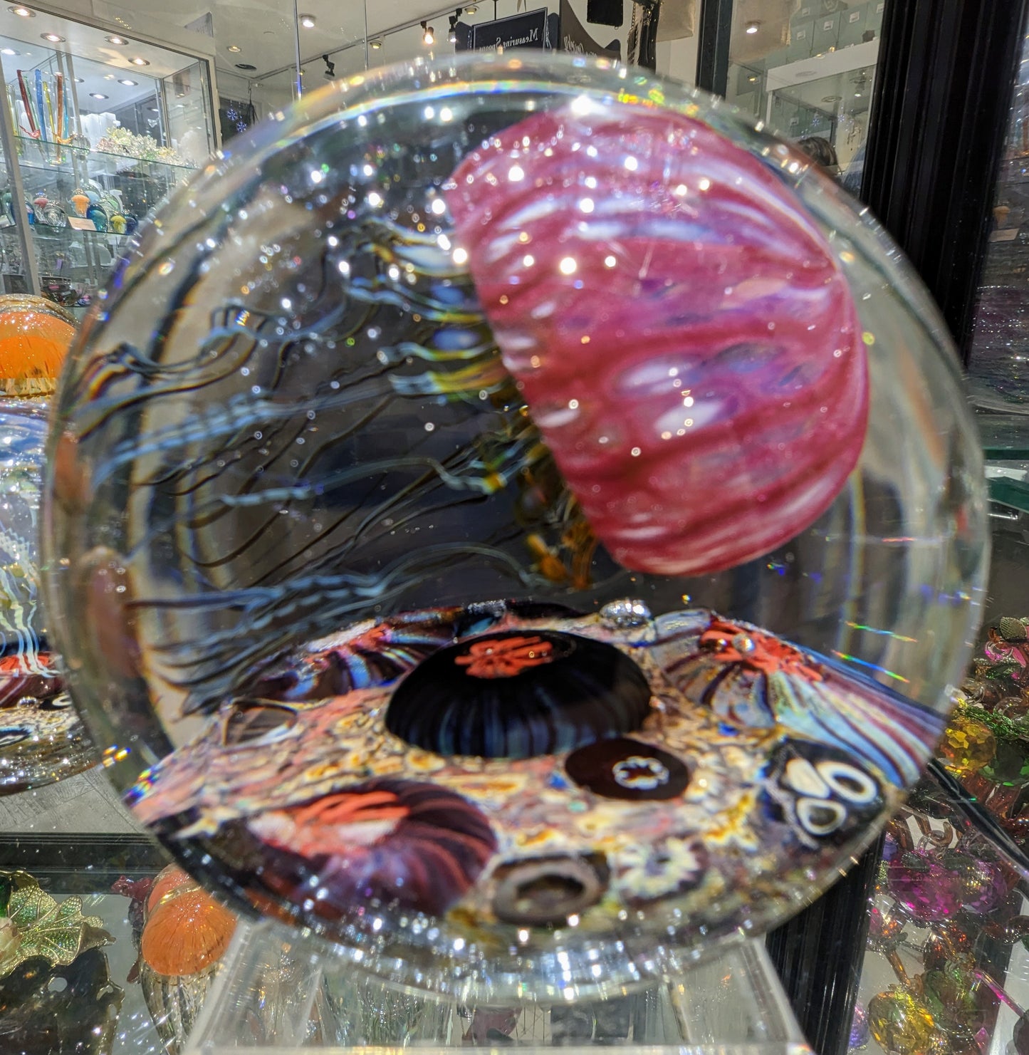 A handcrafted Satava art glass jellyfish sculpture with a gold and ruby colored body