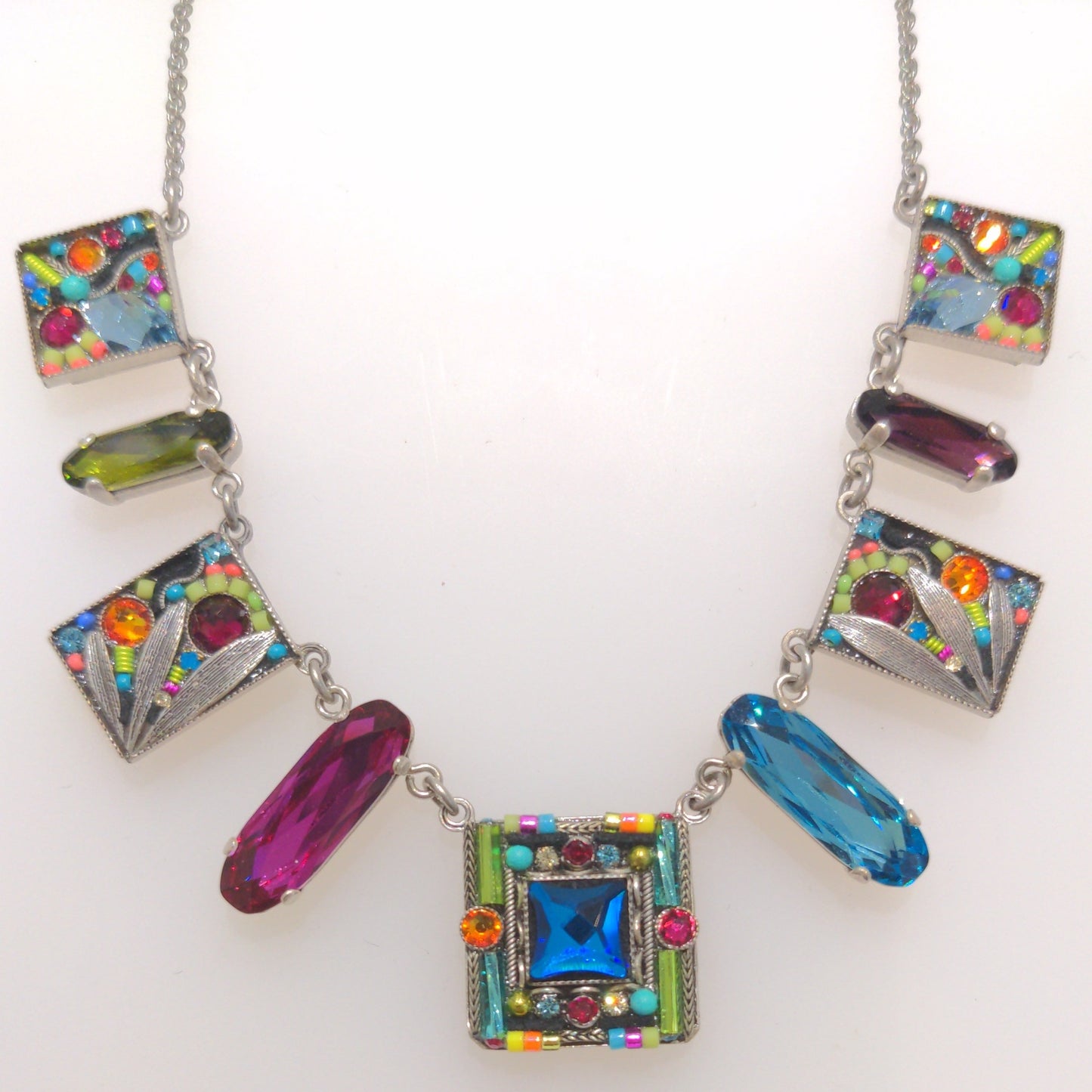 A multicolored Firefly jewelry necklace featuring a series of square and rectangular charms with colorful crystals, and a lobster claw clasp.