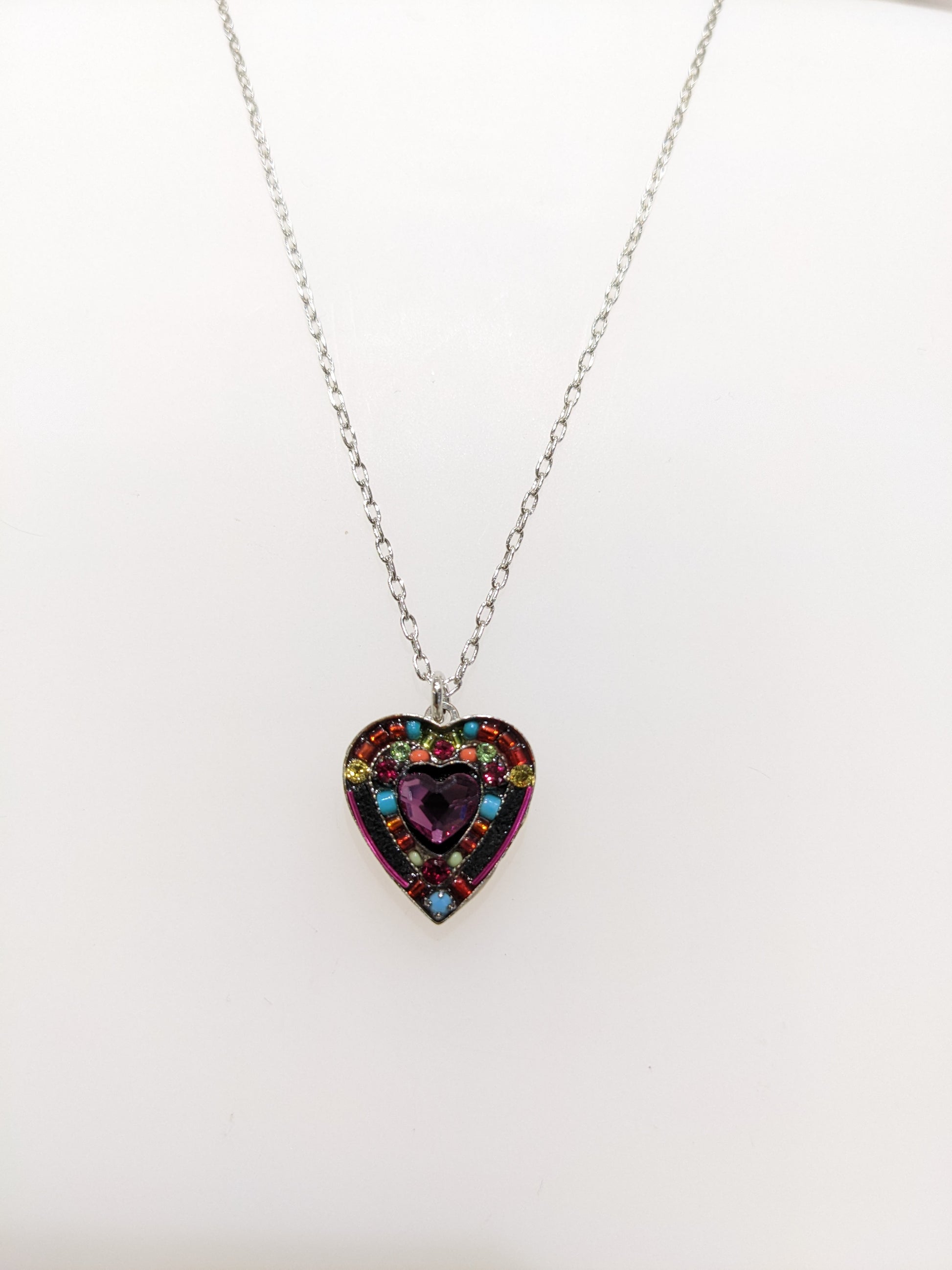 A multicolored heart-shaped Firefly Jewelry necklace on white background.