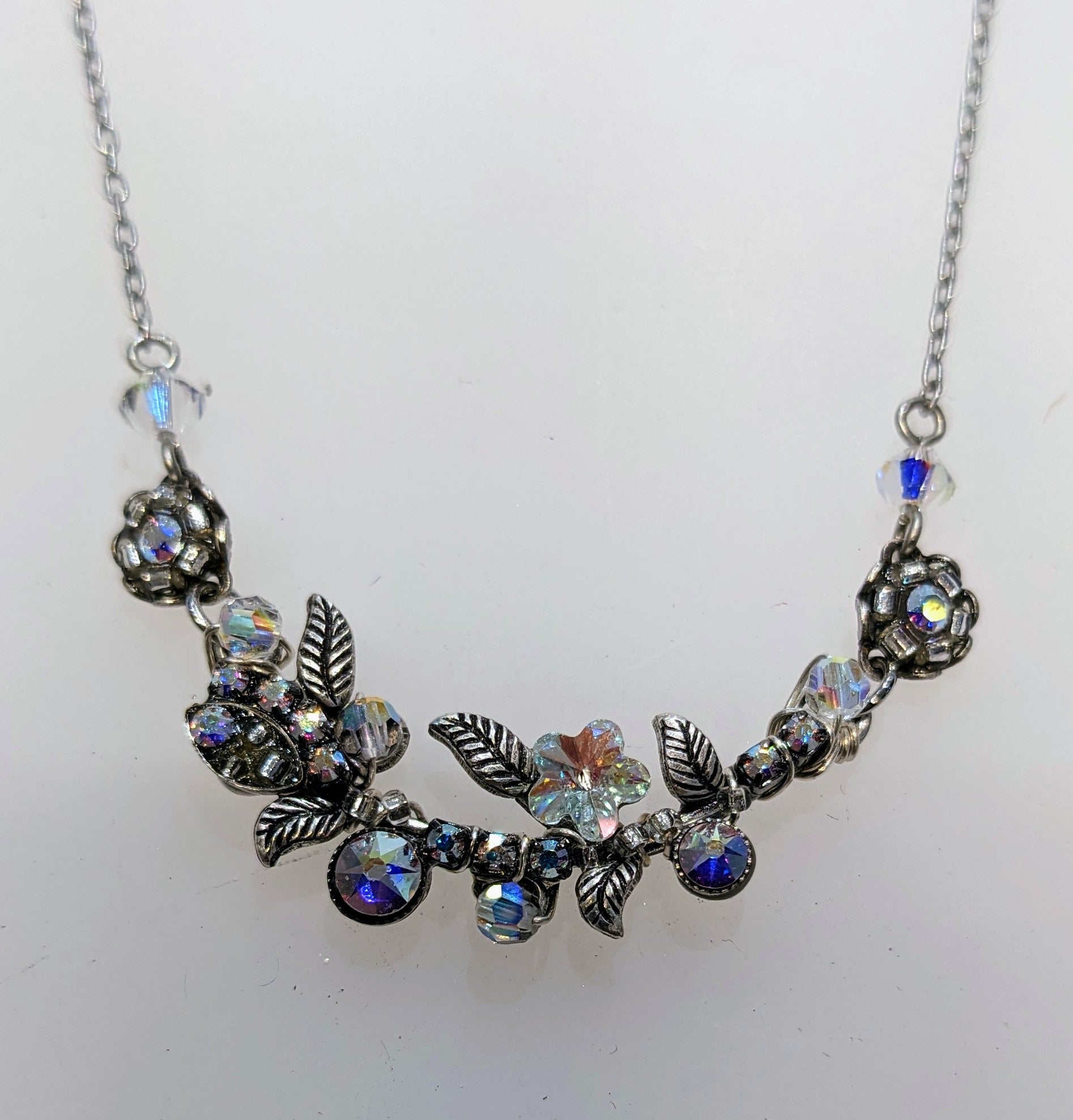 A silver-colored Firefly brand aurora borealis necklace with intricate embellishments and a lobster claw clasp.
