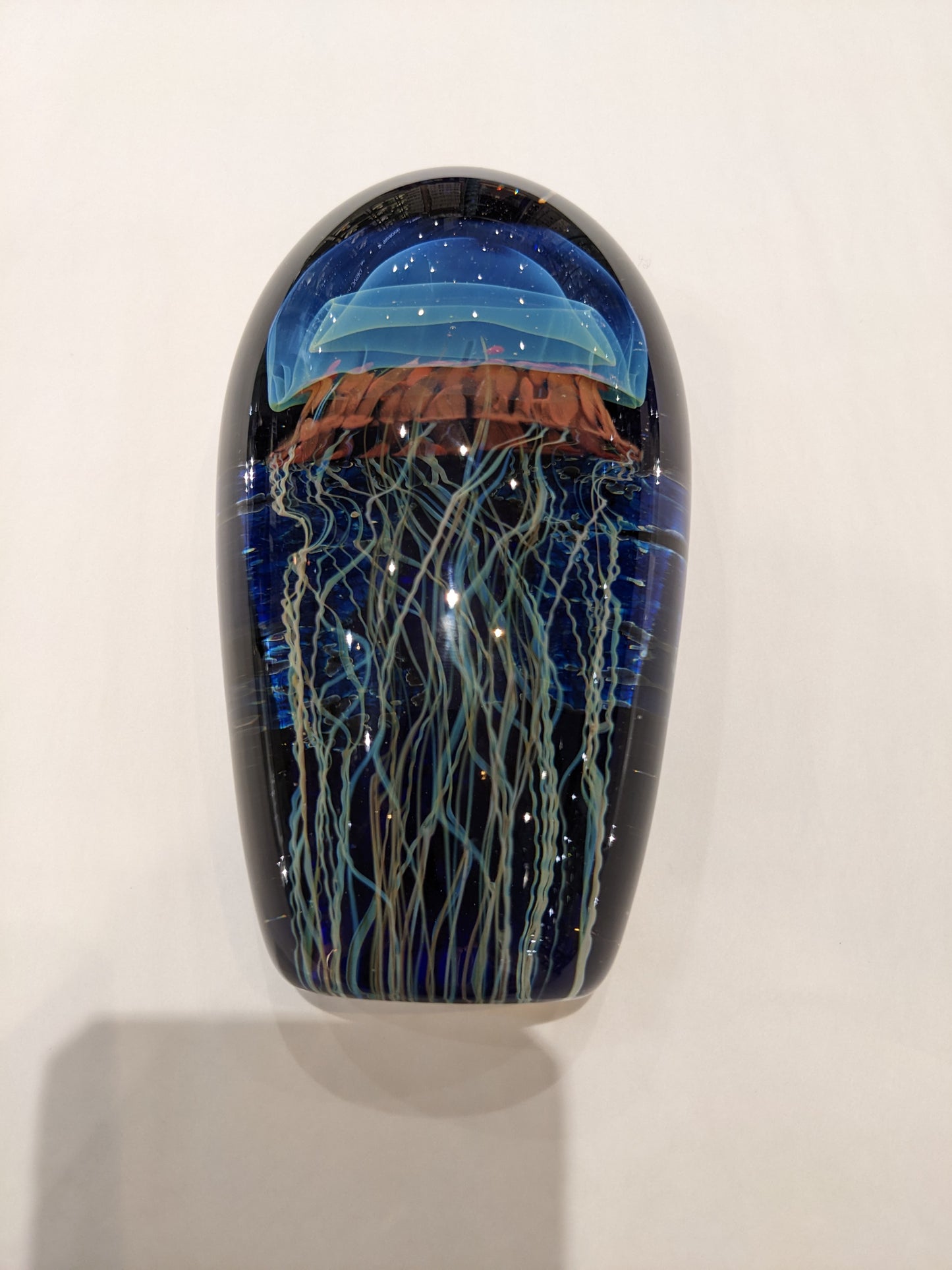 Satava art glass piece with a blue jellyfish design on a moonlit seascape background.