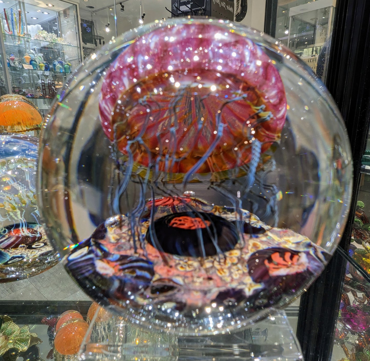 A handcrafted Satava art glass jellyfish sculpture with a gold and ruby colored body inside view