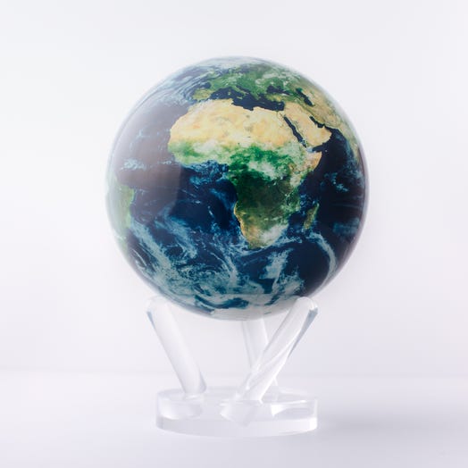 A rotating globe displaying satellite view of Earth with green, blue, and white colors on it, mounted on a clear stand.